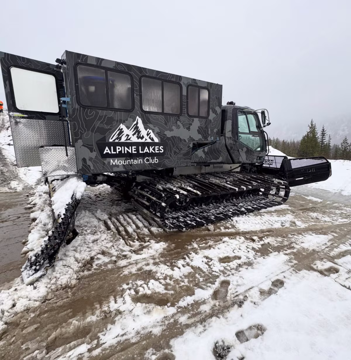 The crew on a snowmobile navigating a washed-out road on the way to the Leavenworth build site